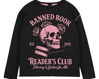 May include: Black long-sleeve shirt with a pink graphic. The graphic features a skull, roses, and the words "BANNED BOOK READER'S CLUB Literacy & Justice for All" with "EST. 2025". The shirt has a pink neckline.