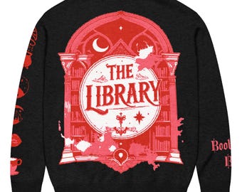 May include: Black long-sleeve sweater with a red graphic on the back that says "The Library." The graphic features a library scene with bookshelves, a crescent moon, and stars. The sleeves have additional red graphics. A cozy sweater for book lovers.