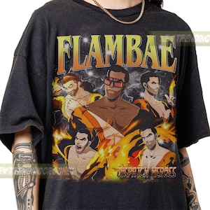 May include: Dark gray t-shirt with a graphic featuring the word "FLAMBAE" in orange and yellow. The graphic includes illustrations of muscular men with flames and lightning. The text "DISPATCH HEROES" is also visible.