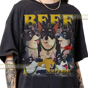 May include: Dark gray t-shirt featuring a graphic of five cartoon dogs with black and white fur, wearing collars and superhero accessories. The word "BEEF" is printed in yellow above the dogs, and "DISPATCH HEROES" is below.