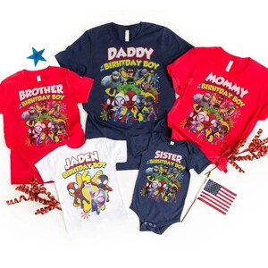 May include: A collection of family birthday shirts in red, navy blue, and white. The shirts feature a colorful graphic of superheroes and the phrases "Daddy Birthday Boy", "Mommy Birthday Boy", "Brother Birthday Boy", "Jaden Birthday Boy", and "Sister Birthday Boy".