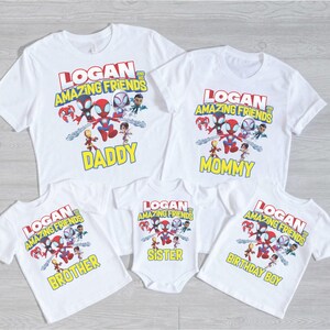 May include: White t-shirts and a onesie featuring a colorful graphic of cartoon superheroes and the text "LOGAN AND HIS AMAZING FRIENDS". The shirts are labeled "DADDY", "MOMMY", "BROTHER", "SISTER", and "BIRTHDAY BOY".