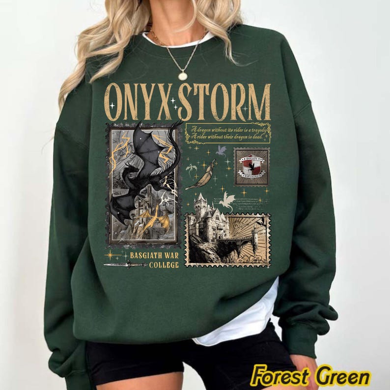 May include: Forest green sweatshirt with the text "ONYX STORM" in gold lettering. The design includes illustrations of a dragon, a castle, and stamps. The text "BASGIATH WAR COLLEGE" is also present.