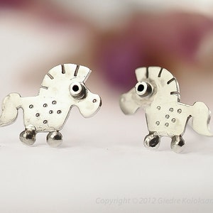 May include: A pair of silver horse stud earrings. The horses are stylised and have a dotted pattern on their bodies.
