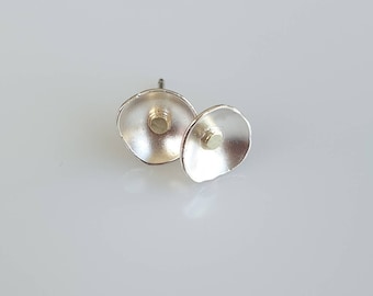 May include: A pair of silver earrings with a small gold dot in the center of each earring.