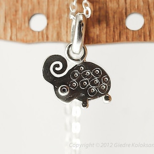 May include: A silver charm necklace with a detailed sheep pendant. The sheep is black and white and has a curly tail.