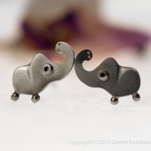 May include: Two small silver elephant earrings, facing each other, with a detailed design.