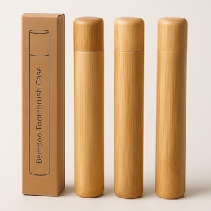 Peut inclure: Trois étuis à brosse à dents cylindriques en bambou avec des dessus et des fonds arrondis. Les étuis sont brun clair et présentent un grain de bois naturel. Une boîte en carton rectangulaire avec le texte "Bamboo Toothbrush Case" est à gauche.