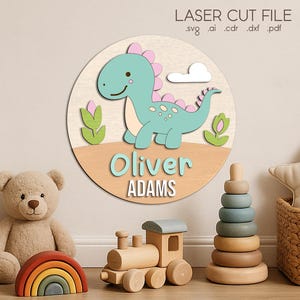 May include: A wooden dinosaur-themed wall sign with the name "Oliver Adams". The sign features a light blue dinosaur with pink accents, a white cloud, and green foliage. The sign is surrounded by children's toys, including a teddy bear and a wooden train.