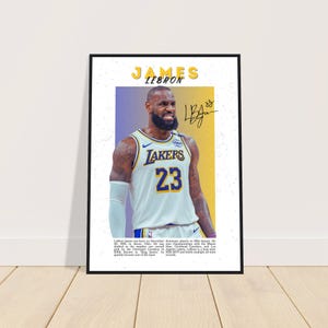 Könnte beinhalten: Gerahmtes Poster mit Basketballspieler LeBron James im Lakers-Trikot mit der Nummer 23. Das Poster hat einen gelb-violetten Hintergrund und den Namen "JAMES LEBRON" oben.