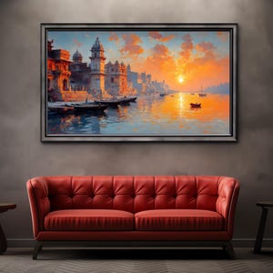 May include: A framed landscape painting depicts a vibrant sunset over a river with buildings and boats. The artwork is displayed above a red tufted sofa, with a dark gray wall and two small wooden side tables.