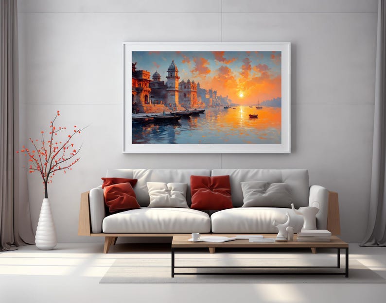May include: A framed landscape painting depicts a vibrant sunset over a river with buildings and boats. The artwork features warm colors, including orange, yellow, and blue, creating a serene and picturesque scene. The painting is displayed above a modern sofa.