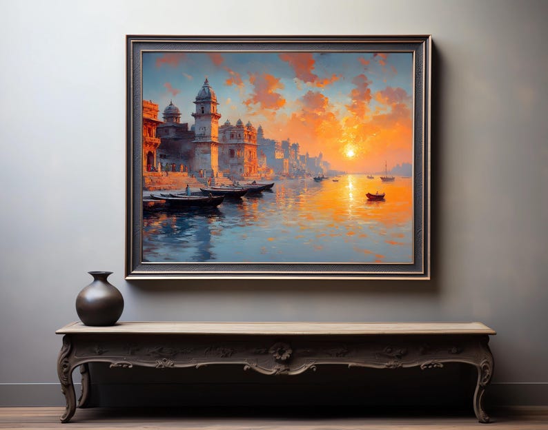 May include: A framed landscape painting depicts a vibrant sunset over a river with boats and buildings. The artwork features warm orange and yellow hues, with a dark frame. A dark vase sits on a decorative wooden table.
