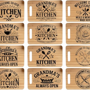 May include: A collection of rectangular wooden cutting boards with various kitchen-themed designs. Each board features a handle and black text, including phrases like "Welcome to Our Kitchen" and "Grandma's Kitchen." The designs include utensils and decorative elements.