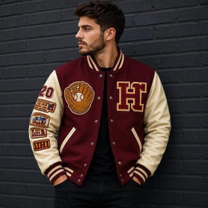 Puede incluir: Una chaqueta universitaria de color granate con mangas color crema, que presenta una letra H grande en el pecho, un parche de guante de béisbol y varios parches rectangulares en la manga derecha, incluyendo el número 20 y texto como IGELA y UHI.