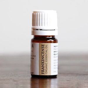 May include: A small brown glass bottle with a white cap, labeled "FRANKINCENSE ORGANIC ESSENTIAL OIL".