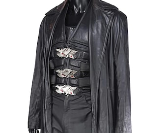 May include: A black leather trench coat and matching outfit displayed on a mannequin. The outfit includes a vest with silver and red accents, and black pants. The coat has a classic lapel and a long, flowing design.