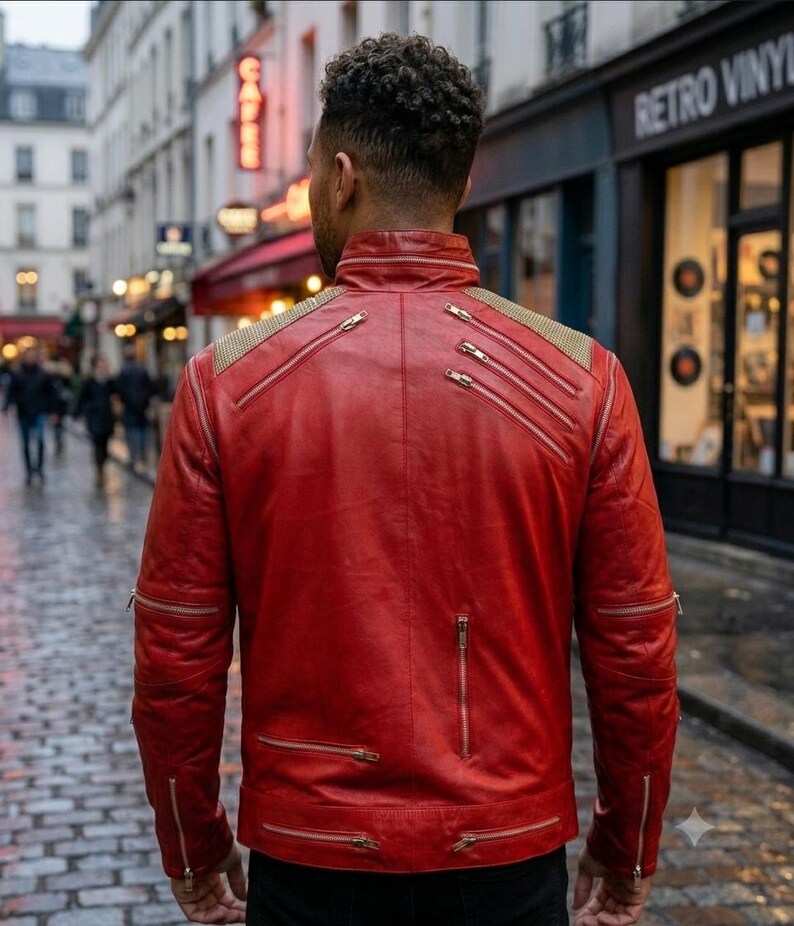May include: A vibrant red leather jacket featuring a high collar, multiple silver-toned metal zippers across the back and sleeves, and textured gold-toned fabric panels on the shoulders. The jacket has a structured fit with visible seams.