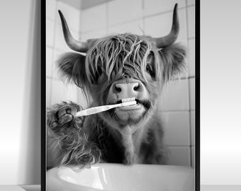 May include: Black and white framed print of a Highland cow brushing its teeth with a toothbrush. The cow is in a bathroom setting, with a white sink and tiled wall in the background. The cow has long, shaggy hair and large horns.