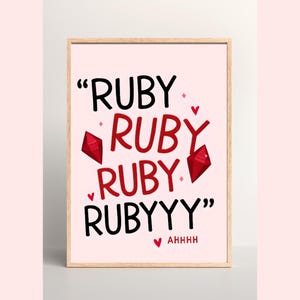 May include: A framed art print with a pale pink background. The print features the word "RUBY" repeated in a playful design, with red gem illustrations and the word "AHHHH" at the bottom. The text is in black and red.