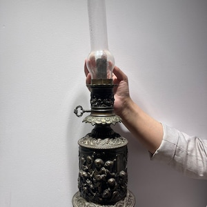 Antieke gegoten metalen olielamp met cherubijnputti-reliëfvoet en glazen schoorsteen Victoria