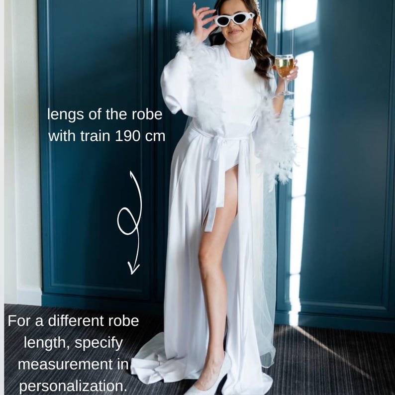 May include: White satin robe with feather trim on the sleeves and a matching belt. The robe's length with train is 190 cm. Text on the image: "For a different robe length, specify measurement in personalization."