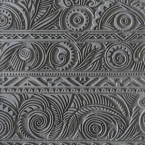 May include: A black and gray patterned rubber stamp with a geometric design. The stamp features a variety of swirls, circles, and lines. The text "Crafttopia.com @ TM565" is printed on the bottom of the stamp.