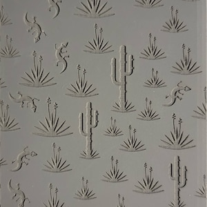 May include: Gray rectangular sheet with embossed desert-themed designs. Features cacti, spiky plants, and lizards. The text "Cabtopia.com" and the number "100470" are at the bottom. The design is a repeating pattern.