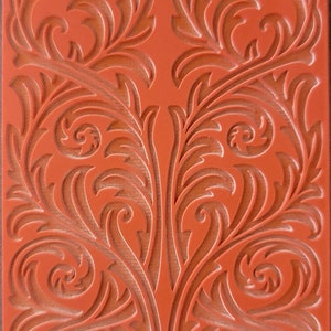 May include: A red rubber stamp with a detailed floral design. The stamp has a raised design and is ready to be used for crafting and decorating projects. The text "Cabtopia.com 100529" is printed on the bottom of the stamp.