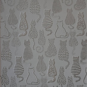 Puede incluir: Una estera de hornear de silicona gris con un patrón repetitivo de gatos en varias poses. Los gatos están delineados en un diseño en relieve y tienen diferentes texturas, incluyendo rayas, puntos y zigzags. La estera tiene el texto "Cabtopia.com 100253" impreso en la esquina inferior derecha.