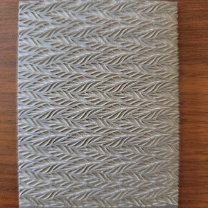 May include: A gray textured silicone mat with a repeating pattern of curved lines. The mat has the text "Cabtopia.com 100102" printed on the bottom.