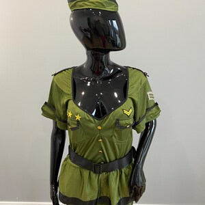 May include: An olive green military-style costume displayed on a mannequin. The outfit features a short-sleeved top with gold star and chevron details, a matching skirt, a black belt, and a peaked cap. The costume has black trim and gold buttons.