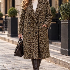 May include: A long, double-breasted coat featuring a brown and black leopard print pattern, wide lapels, and two front pockets. The coat is worn over a cream-colored turtleneck sweater, paired with dark brown knee-high leather boots and a handbag.
