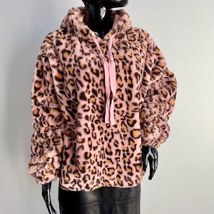 May include: A pink and brown leopard print hoodie with a drawstring hood. The plush fabric has a soft texture. The hoodie is displayed on a black mannequin. The sleeves are gathered at the wrists.