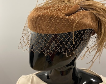 Auténtico sombrero tipo pastillero Kangol de los años 60, color camel, con velo de algodón y plumas, ideal para cócteles. Elegante tocado de diseño vintage británico.