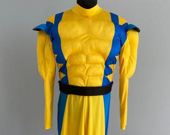 May include: A yellow and blue superhero costume on a mannequin. The costume has a yellow torso with blue detailing, a black belt, and long yellow sleeves. The costume is designed to give a muscular appearance.