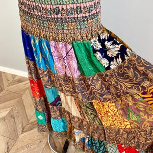 Puede incluir: Falda larga de patchwork con cintura fruncida. La falda presenta una variedad de paneles de tela coloridos con estampados florales y de cachemira. La falda tiene un diseño escalonado con un dobladillo con volantes, creando un estilo bohemio.