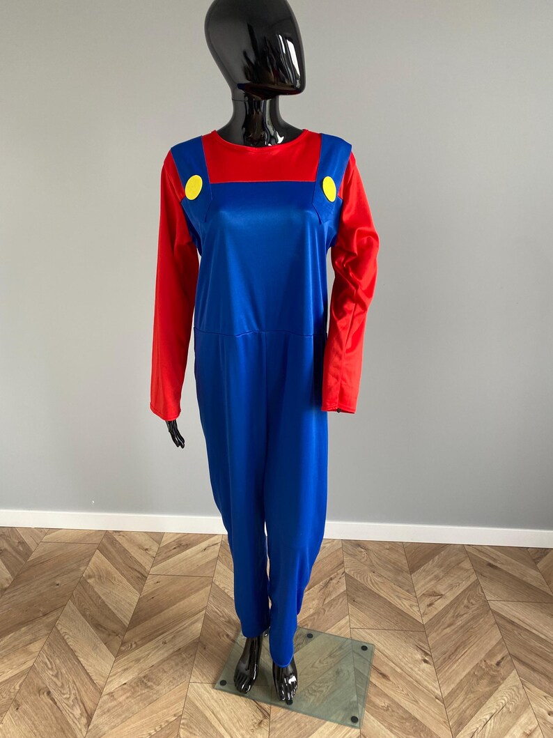May include: A long-sleeved jumpsuit featuring a vibrant red shirt top integrated with blue overalls. The design includes two large, bright yellow circular buttons positioned at the top of the blue overall straps on the chest area.