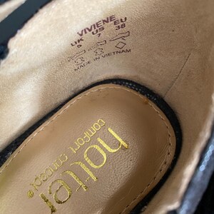 May include: The interior of a black shoe with a tan insole featuring the gold text 'hotter' and 'comfort concept'. The side wall displays the text 'VIVIENE', 'UK 5', 'US 7', 'EU 38', and 'MADE IN VIETNAM' along with icons representing shoe construction.