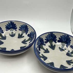 May include: A white ceramic mug with a black handle and the text "But First, Coffee" in a black, bold font. The mug is sitting on a white surface.