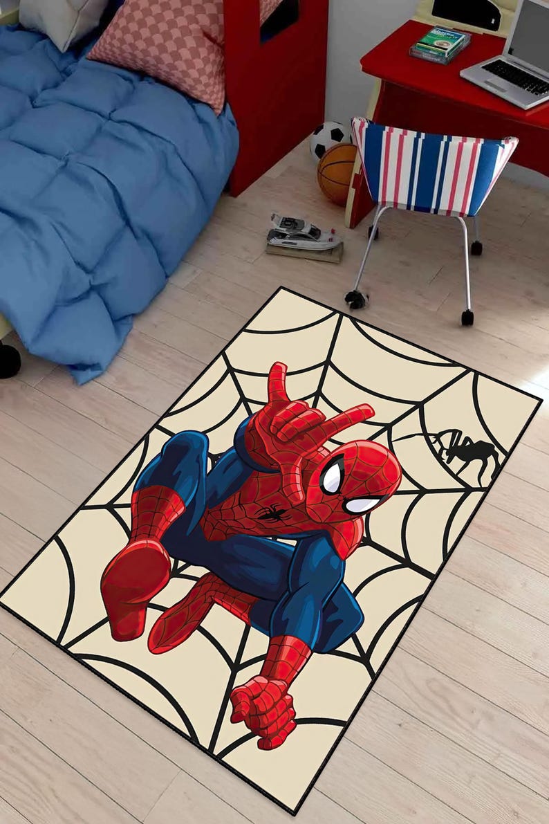 May include: A rectangular rug featuring a Spider-Man illustration. The superhero is depicted in his classic red and blue suit, posed against a cream-colored background with a black spiderweb design. A black spider silhouette is in the corner.