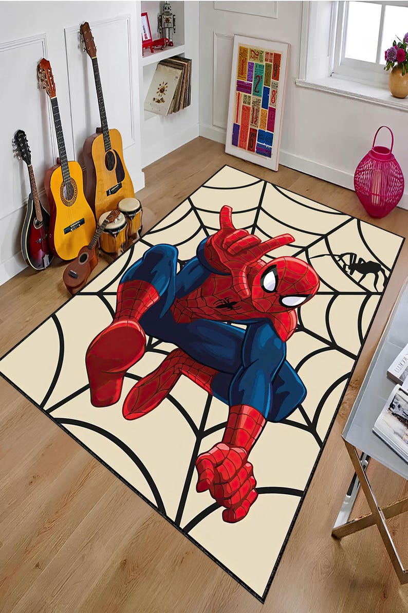 May include: A rectangular rug featuring a large illustration of Spider-Man in a dynamic pose, set against a cream-colored background with a black spiderweb design. The superhero is depicted in his classic red and blue suit.