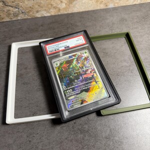 Op de afbeelding: Een beoordeelde Pok&eacute;mon-kaart in een zwarte hoes, met een kleurrijke illustratie van Scovillain. De kaart is gelabeld met "2023 Pok&eacute;mon SV1EN Scovillain Illustration Rare" en is omgeven door witte en groene frames.