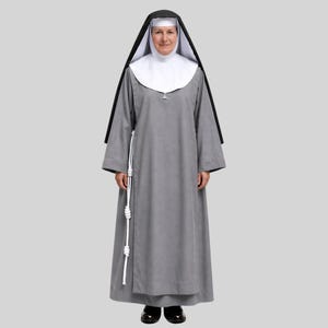 May include: A floor-length grey habit with long sleeves, paired with a white wimple and a black veil. A white rope cincture with multiple knots hangs from the waist. The garment is worn with dark shoes, creating a traditional religious ensemble.