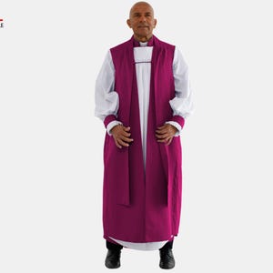 Könnte beinhalten: Eine Person trägt ein magentafarbenes Geistlichen-Gewand über einer weißen Robe mit langen Ärmeln. Das Gewand hat ein langes, fließendes Design. Die Ärmel haben weiße Manschetten mit Spitzensaum. Das Clergy Attire-Logo befindet sich in der oberen linken Ecke.