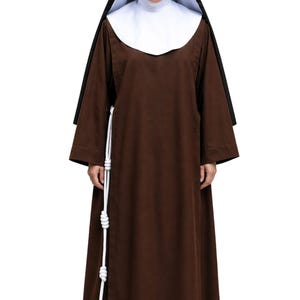 以下が含まれることがあります： 長袖で床までの長さのスカートが付いた茶色の修道服。白いウィンプルと黒いベールを合わせています。腰には3つの結び目がある白いロープベルトが垂れ下がっています。ダークブラウンの靴を履いています。