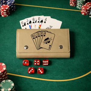 May include: A tan leather card holder with a hand of cards and the name "SMITH" printed on the Ace of Spades. Five red dice are scattered on a green felt surface, along with poker chips and a deck of cards.