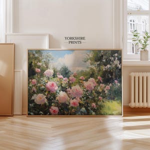 Puede incluir: Una pintura enmarcada que representa un jard&iacute;n de rosas rosas en plena floraci&oacute;n. La obra de arte, con el texto "YORKSHIRE PRINTS", presenta una escena pintoresca con flores vibrantes sobre un fondo de vegetaci&oacute;n y cielo nublado.