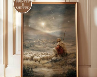 May include: A framed wall art print featuring a shepherd in a red robe and tan cloak sitting on a hill with a staff, overlooking a flock of sheep and a distant town under a night sky with a bright star. The text YORKSHIRE PRINTS is visible.