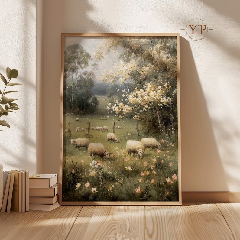 Op de afbeelding: Een ingelijst schilderij van een pastorale landschap met een kudde schapen die grazen in een weide vol wilde bloemen. Het kunstwerk heeft een zacht, gedempt kleurenpalet en een serene sfeer.